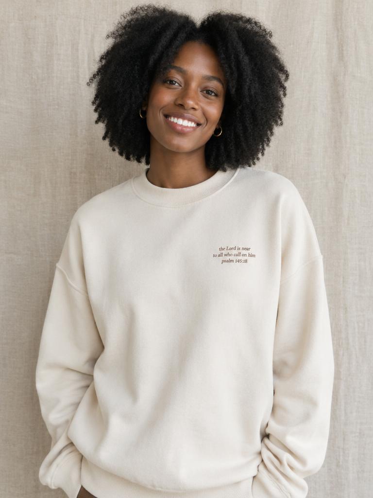 Woman wearing an oversized cream scripture crewneck sweater